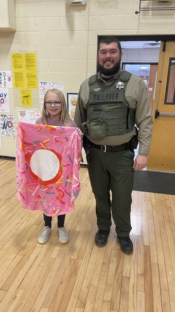 A student dressed as a donut poses for a picture with a police officer. 