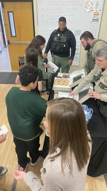 Students are in line to receive donuts from several police officers.