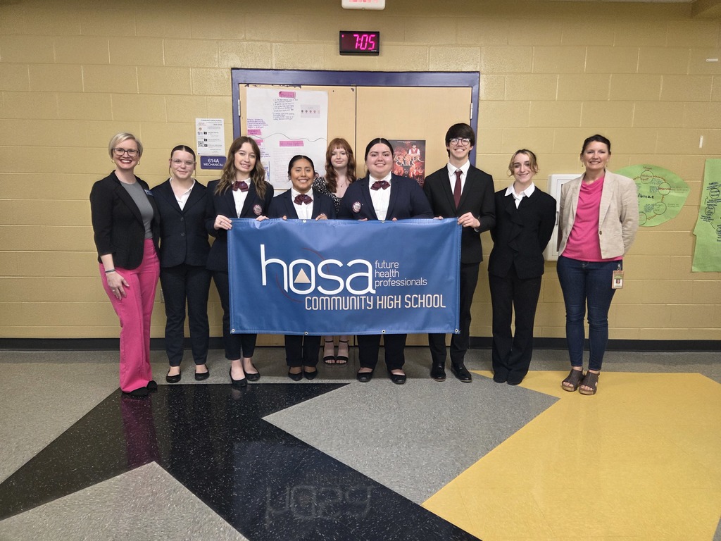 Students and teachers pose for a picture holding  a Community High School HOSA banner. 