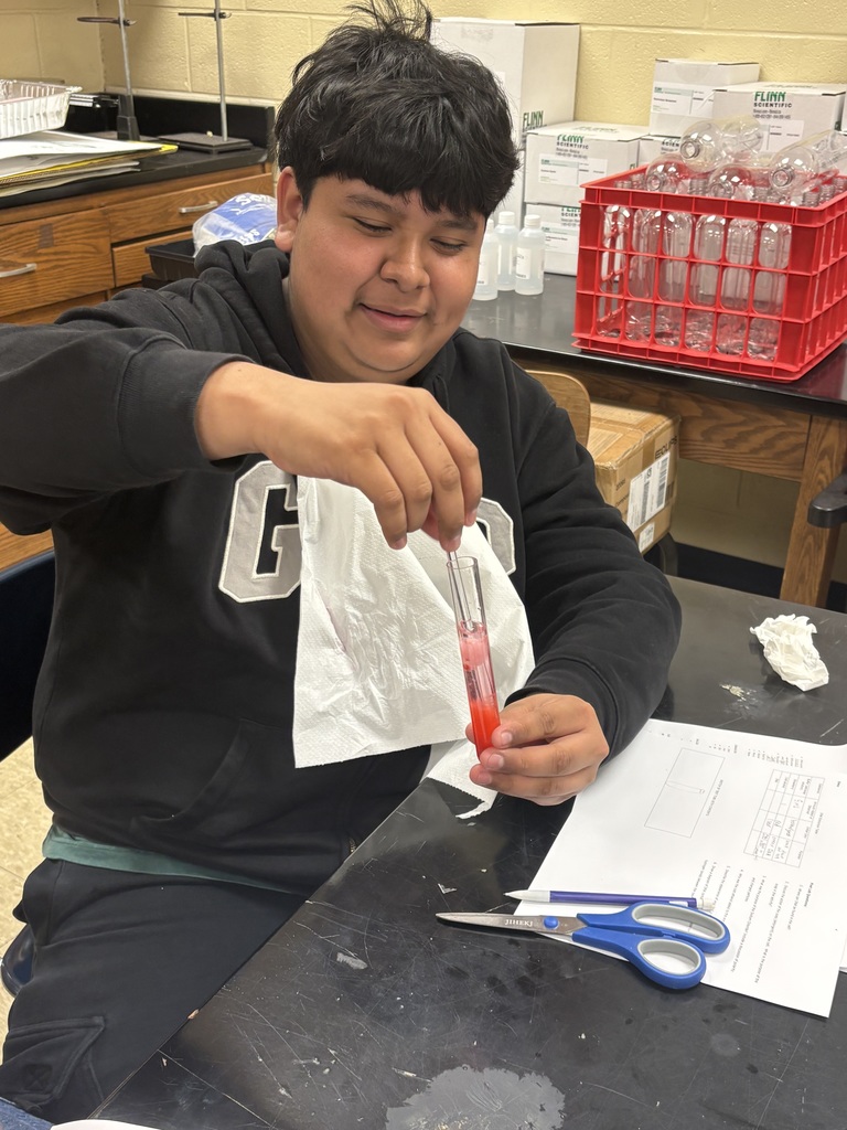 Student holding a test tube containing a strawberry.