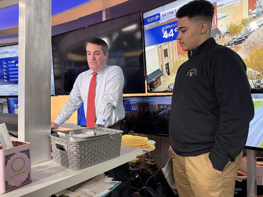 Student talks with meterologist while looking at a computer. 