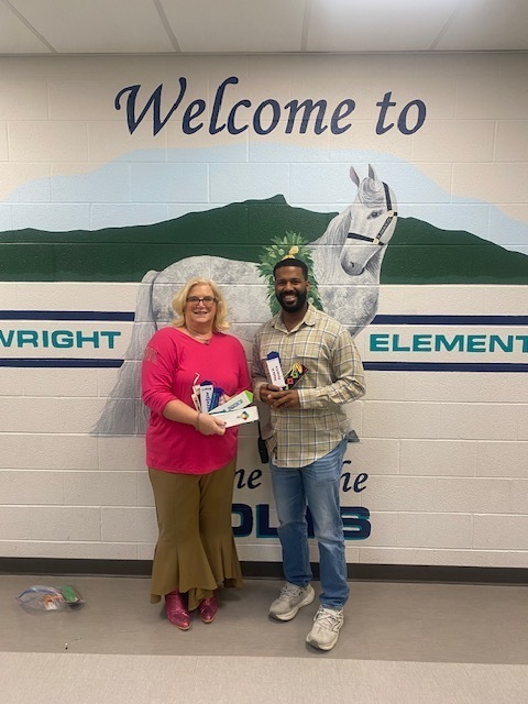 Picture of two people against a wall holding handstitched bookmarks. 