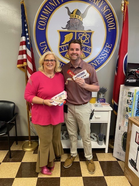 Picture of two people against a wall holding handstitched bookmarks. 