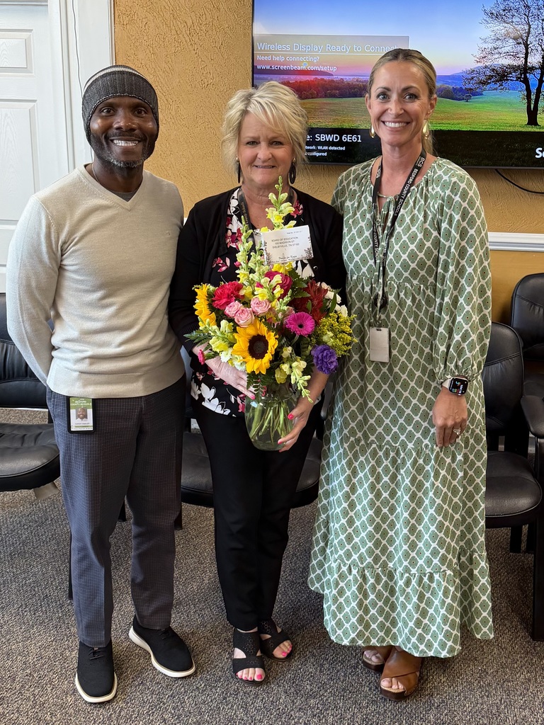 Instructional Coach of the Year Lee Ann Butts receives flowers from two people as they pose for a picture. 