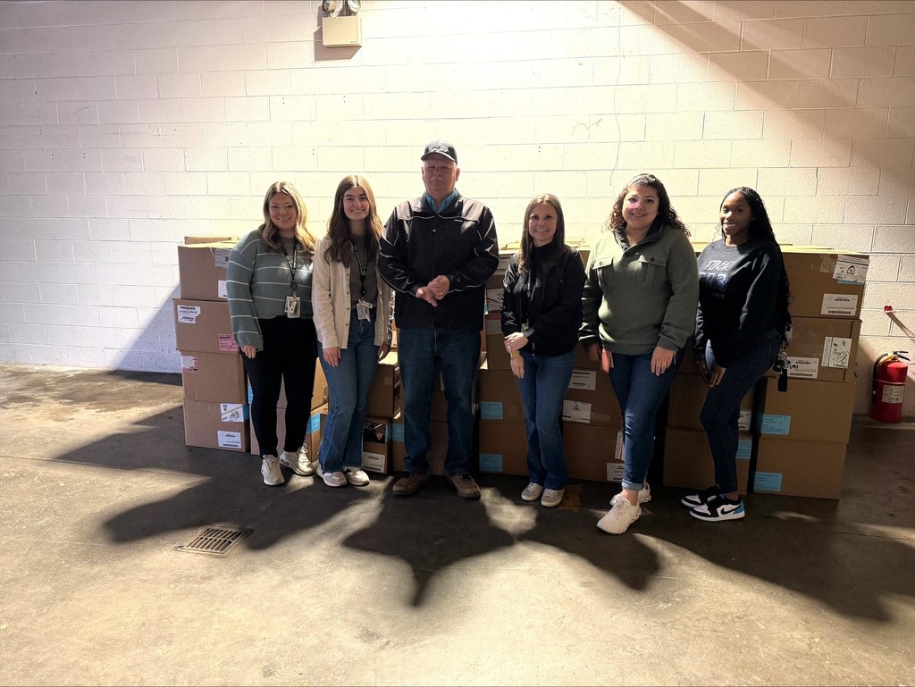 Group of people standing in front of food boxes that were packed for spring break.