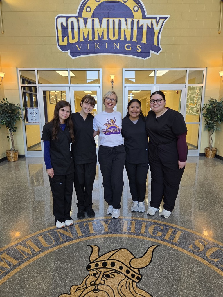 Group photo of five people standing in front of the main entrance doors at Community High School.