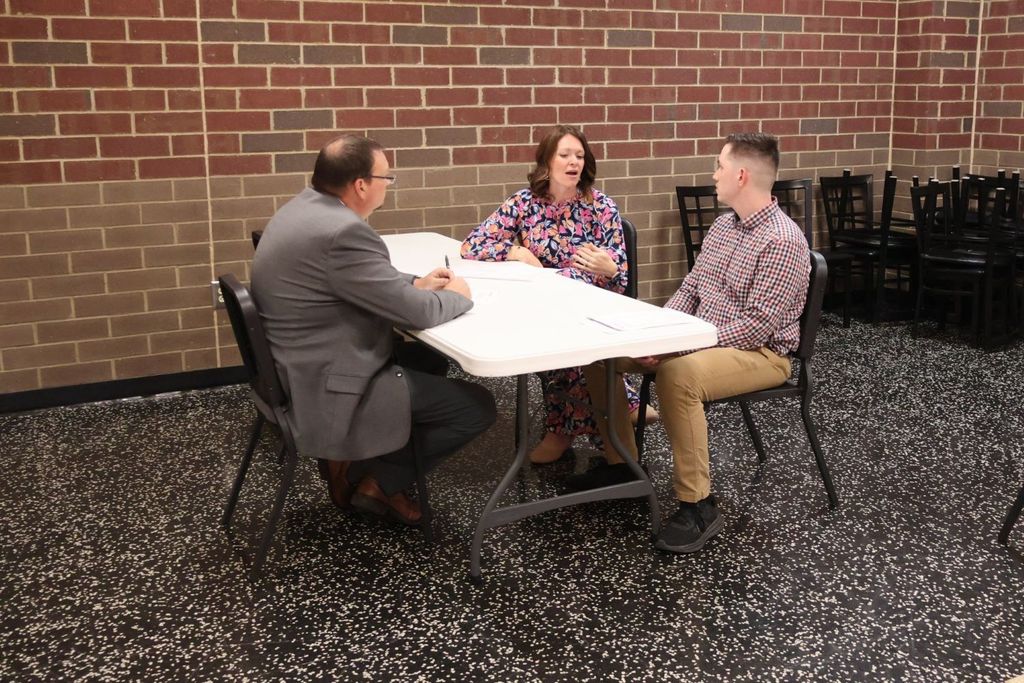 Administrators speaking with person at Teacher Recruitment Fair.