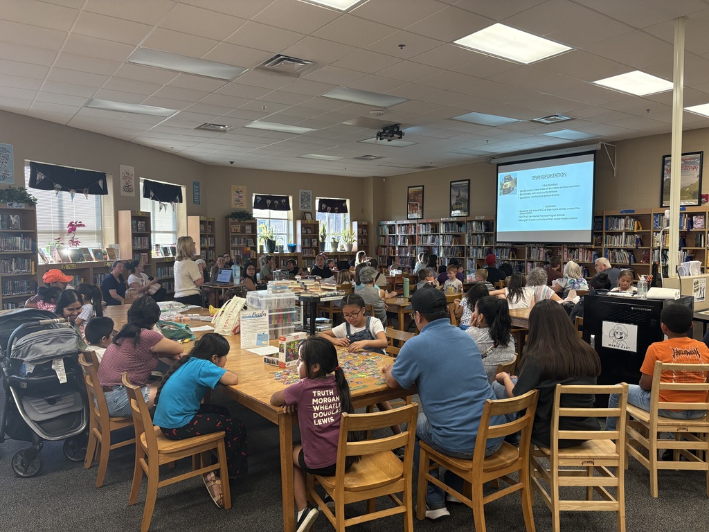 Group of parents and their children meeting in the library to learn more about Summer Learning Camp/Summer School.