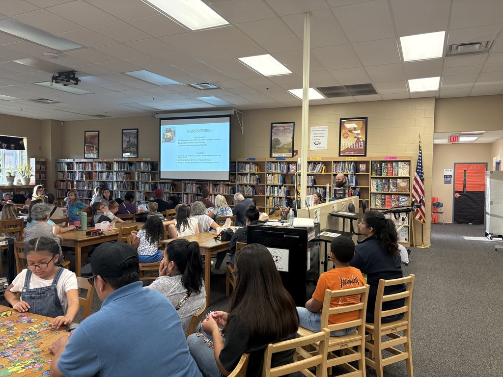 Group of parents and their children meeting in the library to learn more about Summer Learning Camp/Summer School.