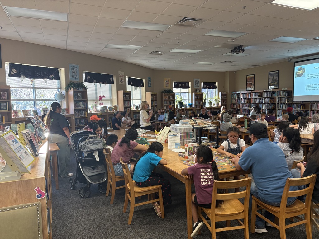 Group of parents and their children meeting in the library to learn more about Summer Learning Camp/Summer School.