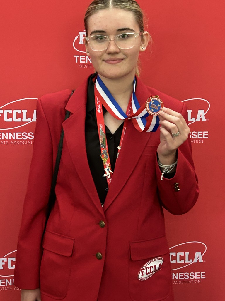 Student is holding up a medal that she won.