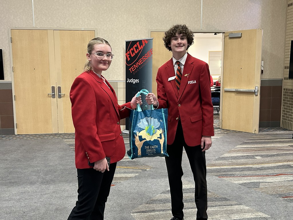 Students are holding up a bag they packed to support the troops. 