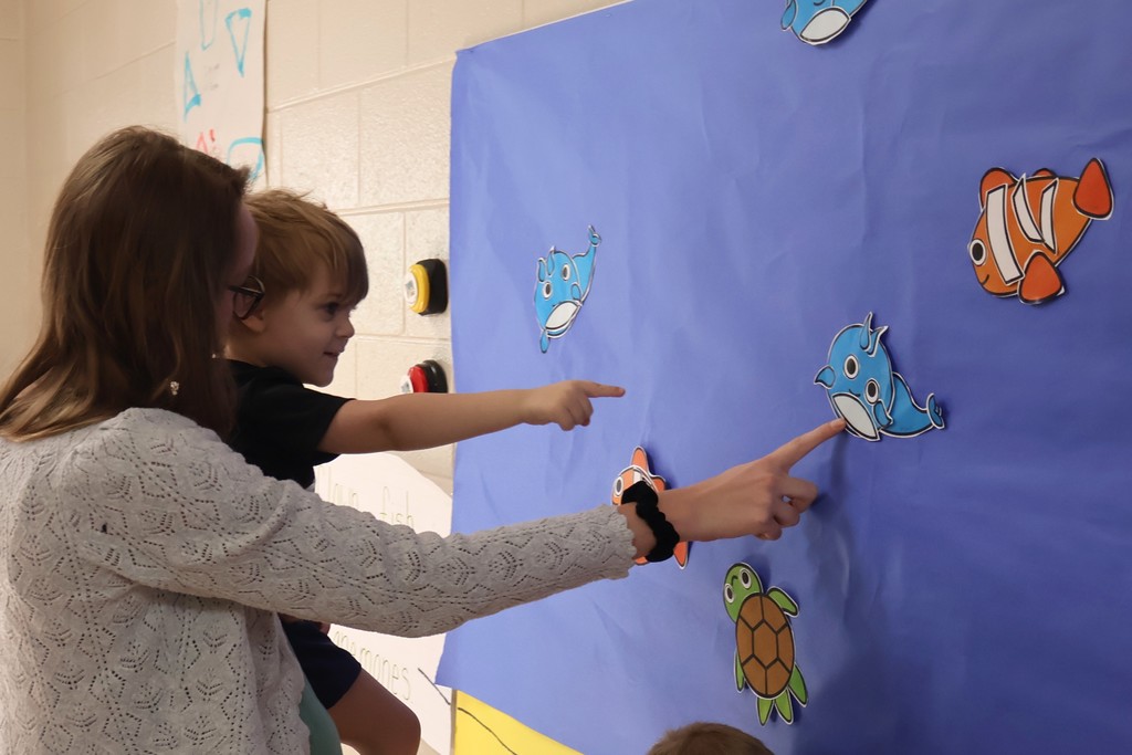 Students and their teacher are looking at the interactive coral reef exhibit at Eakin Elementary school. 