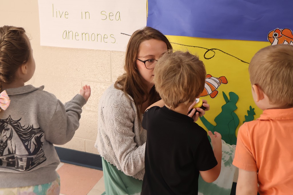 Students and their teachers are pressing buttons at the interactive coral reef exhibit at Eakin Elementary school. 