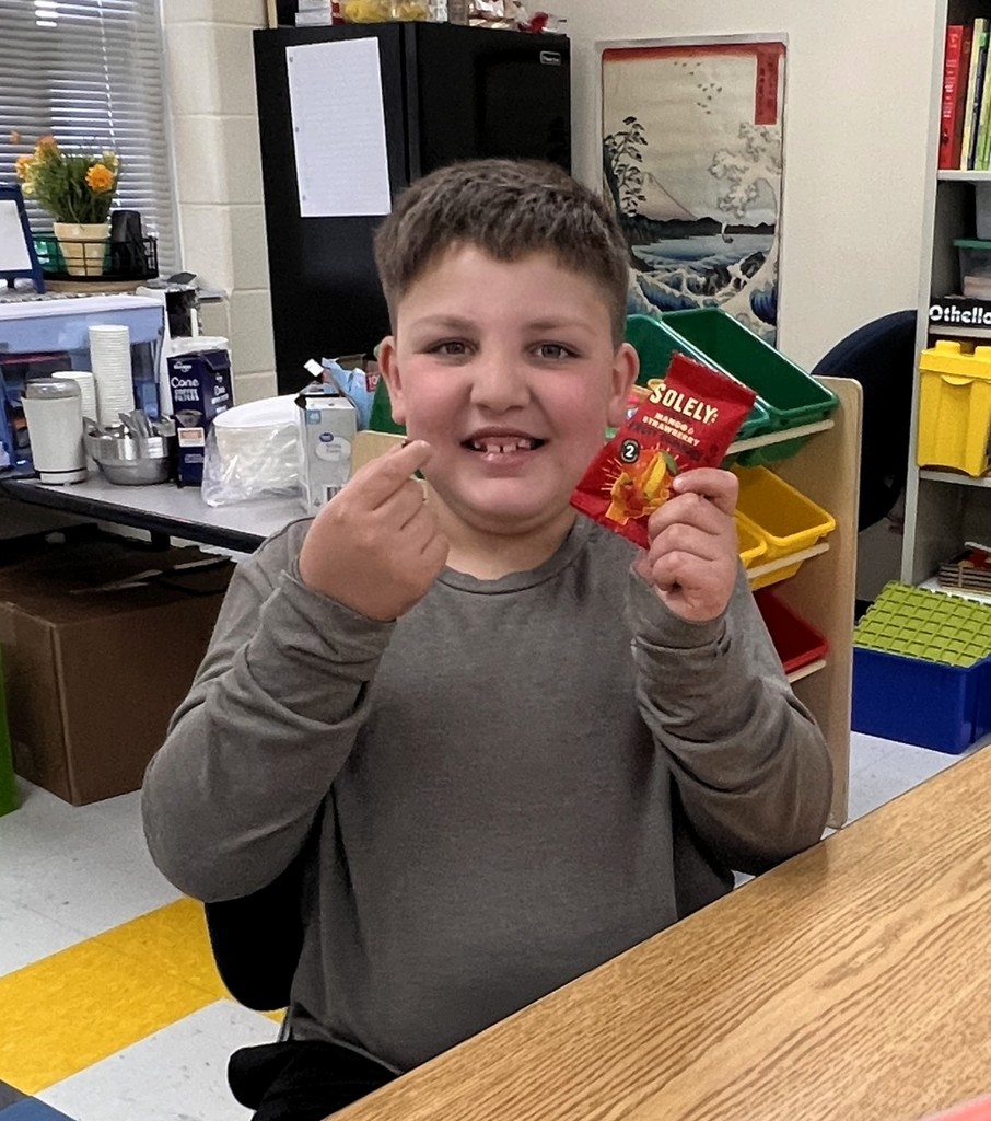 A student holds up a food that he is about to taste.