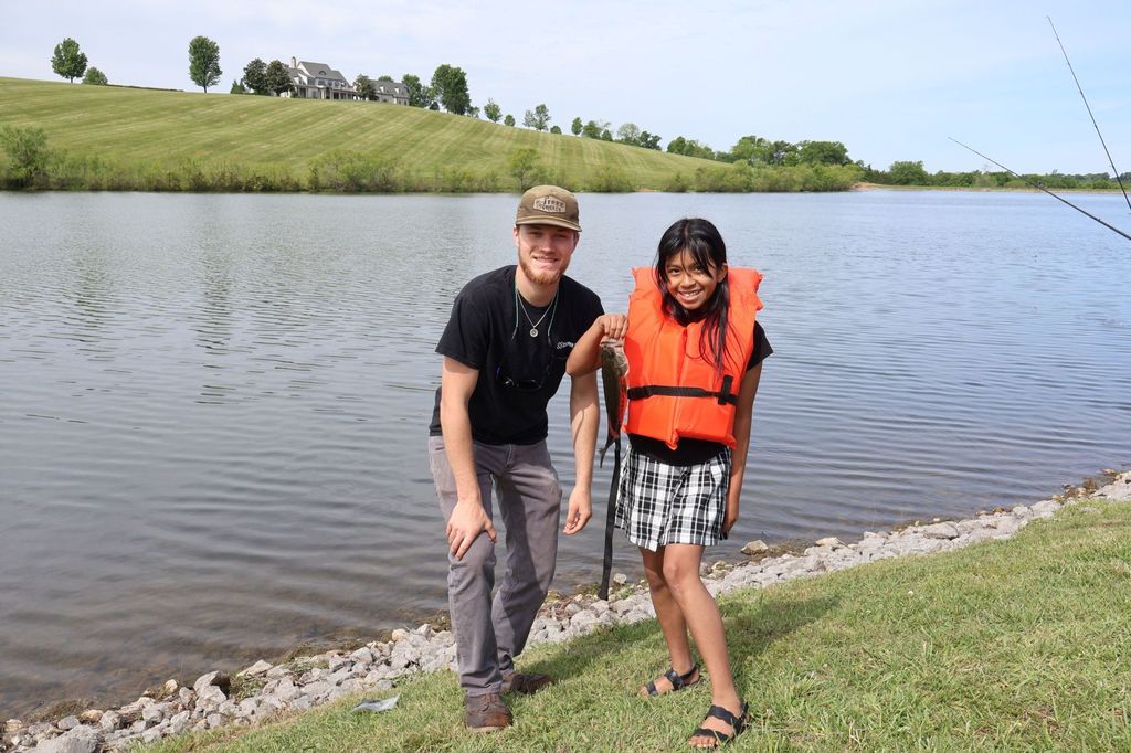 Adult and a student pose for a picture holding a fish. 