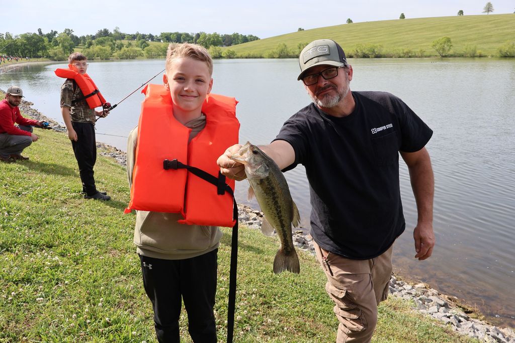 Adult and a student pose for a picture holding a fish. 