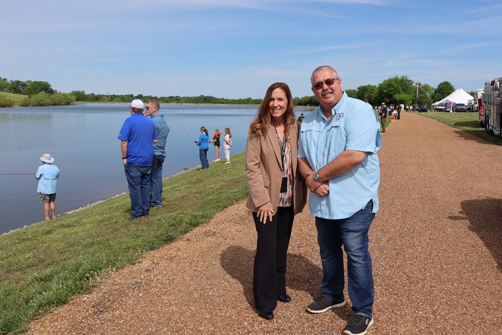Two people pose for a picture with the lake in the background at the Cops and Bobbers event. 