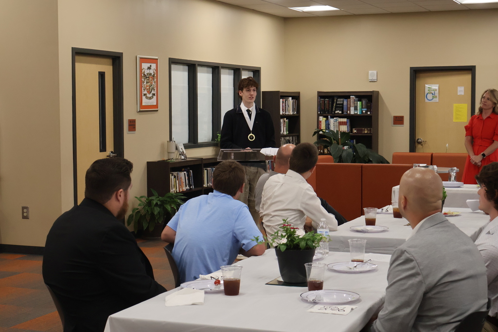 Group photo of everyone attending the luncheon while someone speaks at the podium. 