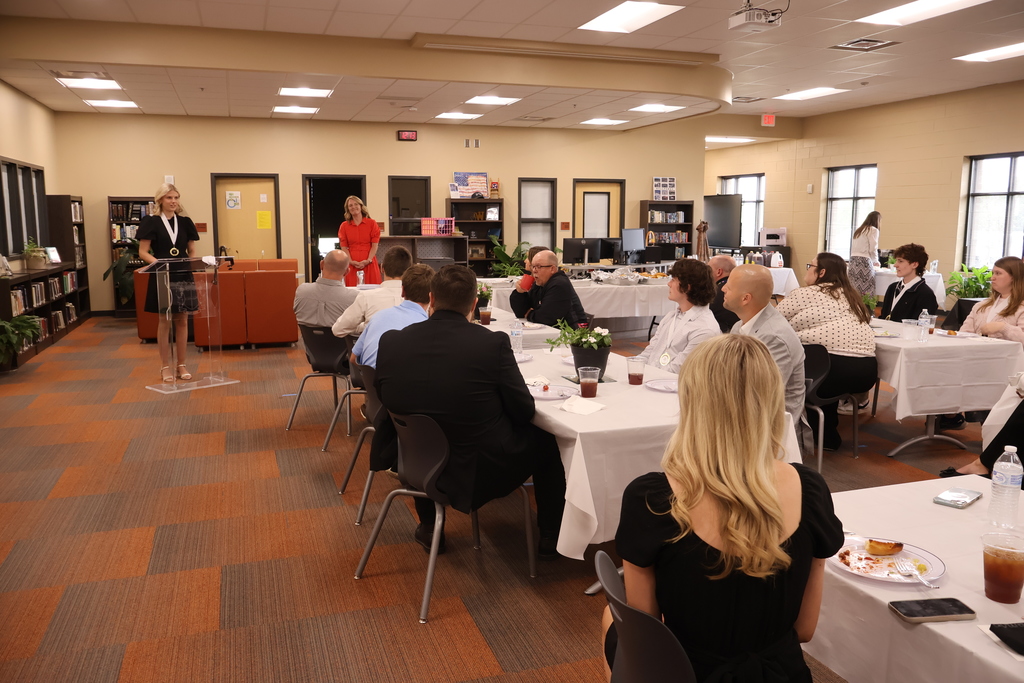 Group photo of everyone attending the luncheon while someone speaks at the podium. 