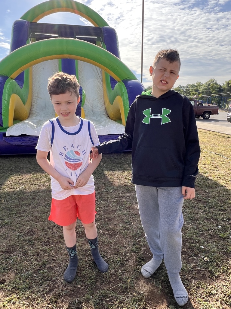 Two students pose for a picture in front of a inflatable slide. 