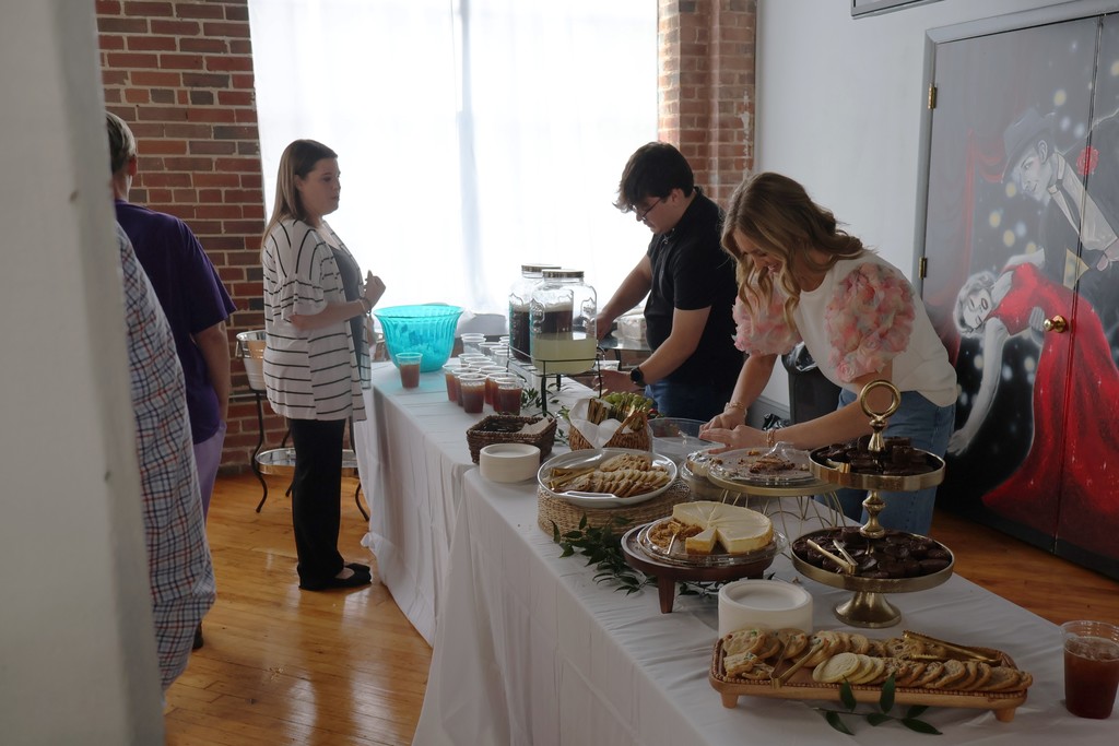 Two people are serving drinks and desserts at a table.