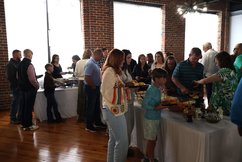 People standing in line, filling their plates to eat. 
