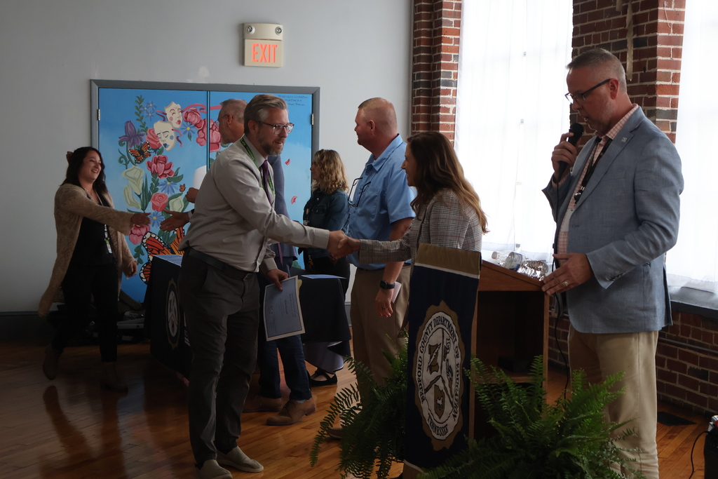 A person is receiving their certificate from the superintendent.