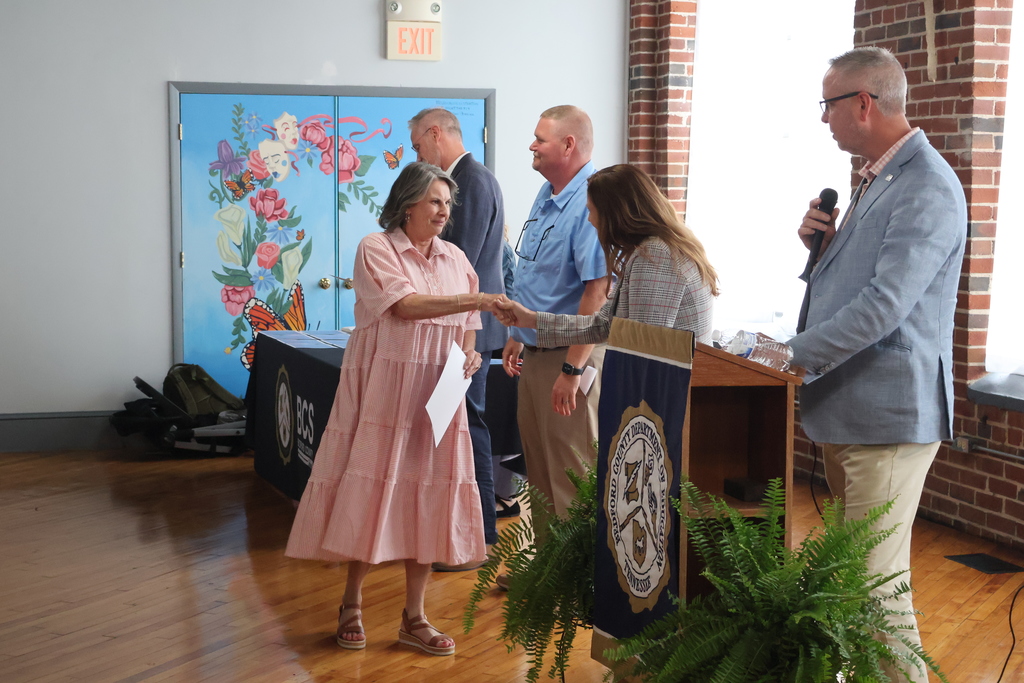 A person receiving their certificate from the superintendent.