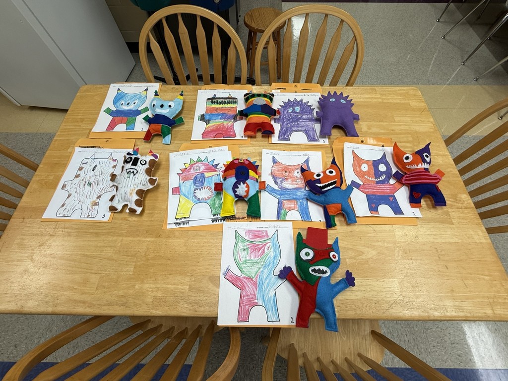 All of the completed monsters are laying on a table along with their original drawings.