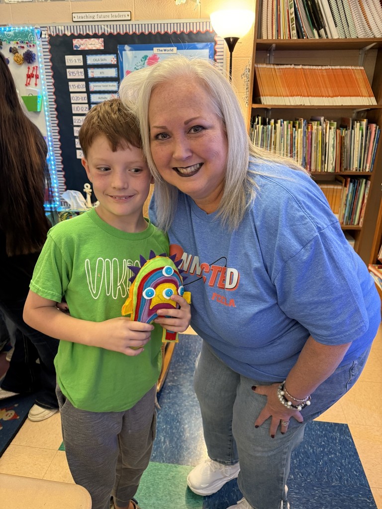 A teacher poses with a student holding his "friendly monster".