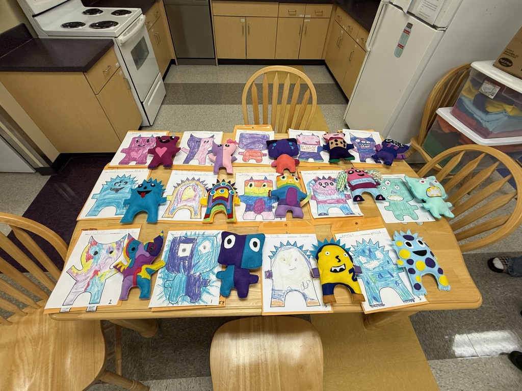All of the completed monsters are laying on a table along with their original drawings.