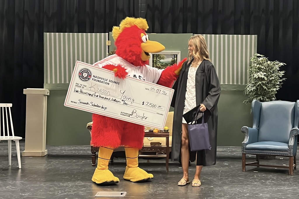 A student from Cascade High School receives a scholarship check from the Nashville Sounds mascot. 