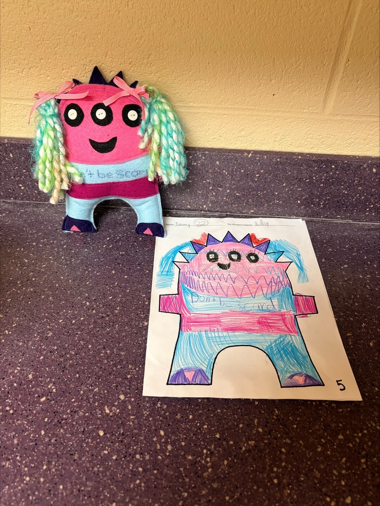 The finished friendly monster is posed behind the drawing of it. 