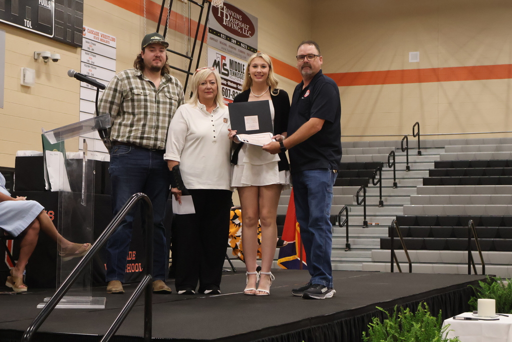 A student receives a scholarship from three people on the stage. 