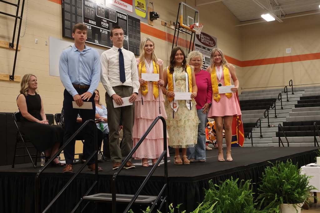 A group of seniors receive a scholarship on stage and are posed for a picture. 