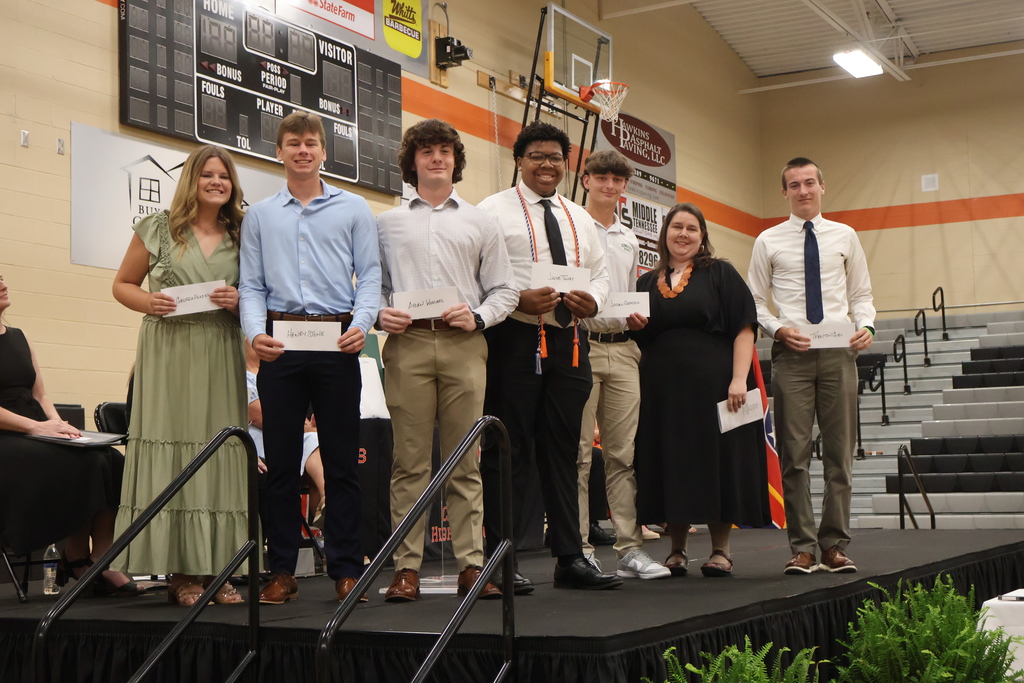 A group of seniors receive a scholarship on stage and are posed for a picture. 