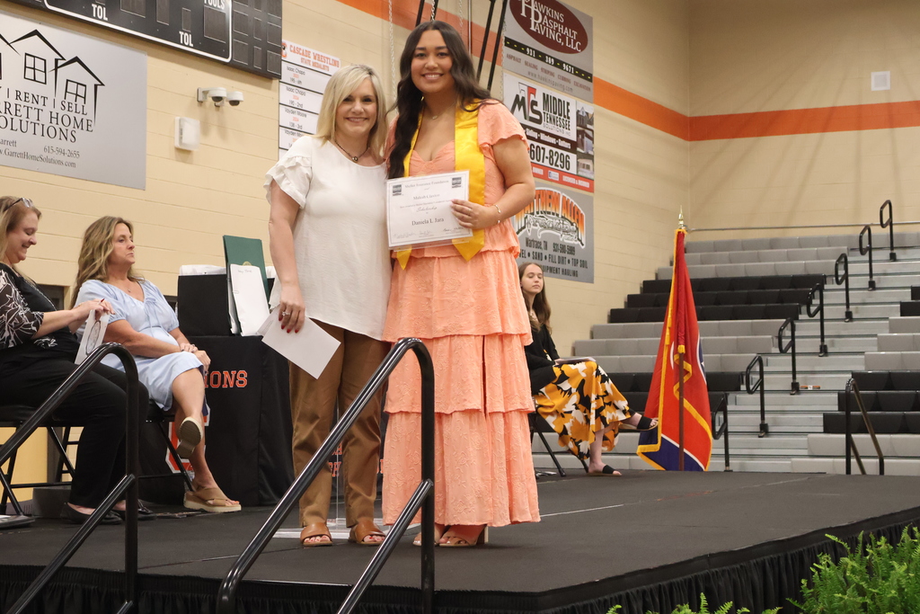 A student receives a scholarship from someone on the stage. 