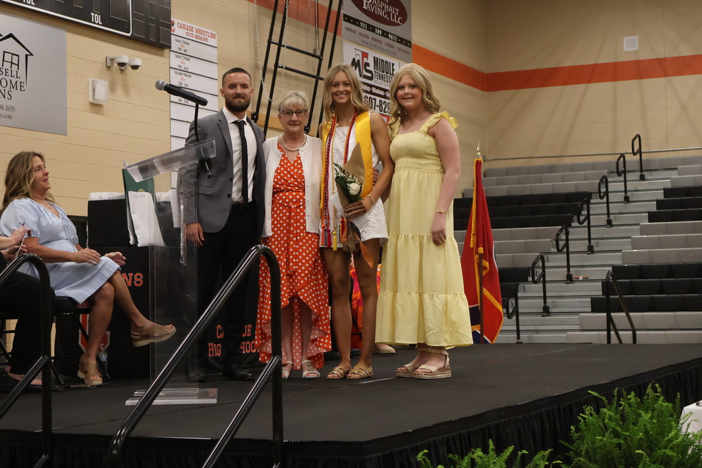 A student receives a scholarship from three people on the stage. 
