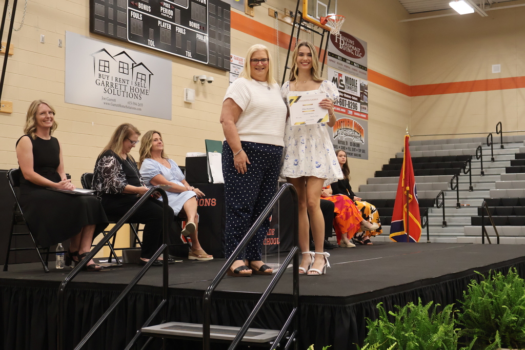A student receives a scholarship from someone on the stage. 