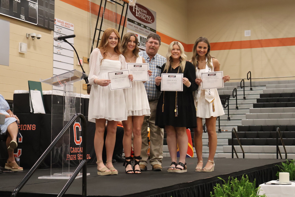 A group of seniors receive a scholarship on stage and are posed for a picture. 