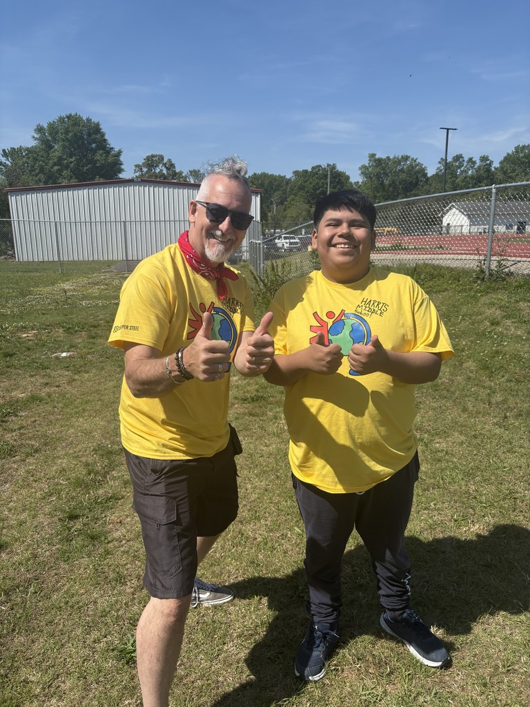 A student and their teacher poses for a picutre while both giving a thumbs up. 