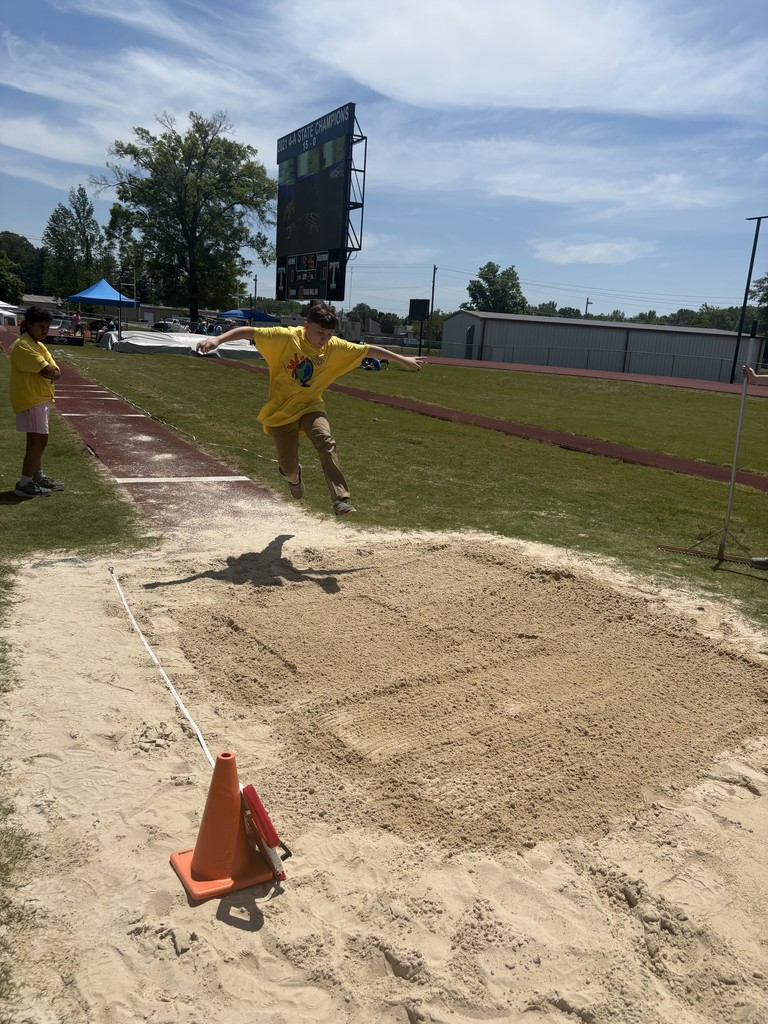 A student is participating in an event while jumping into sand. 