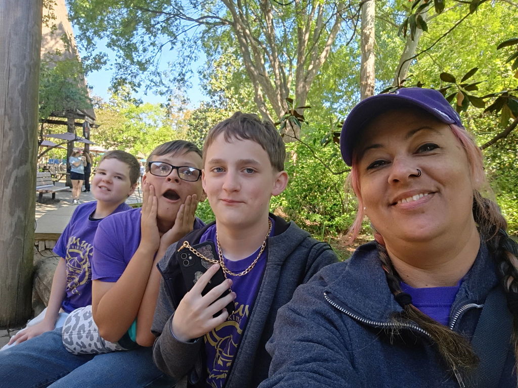 Three students are posed for a group picture with an aide.