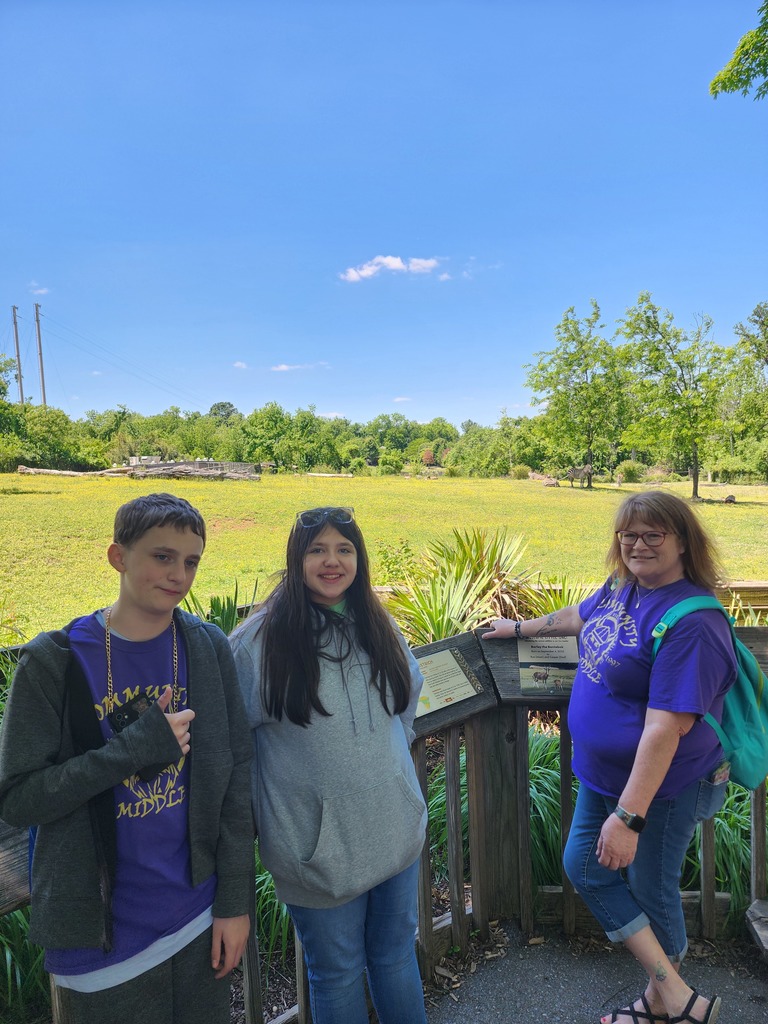 Two students are posed with a picture in front of a zoo exhibit.