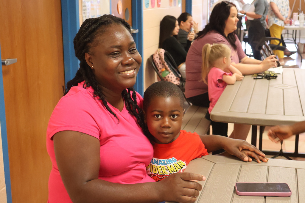 A boy and his mom pose for a picture while sitting at a table. 