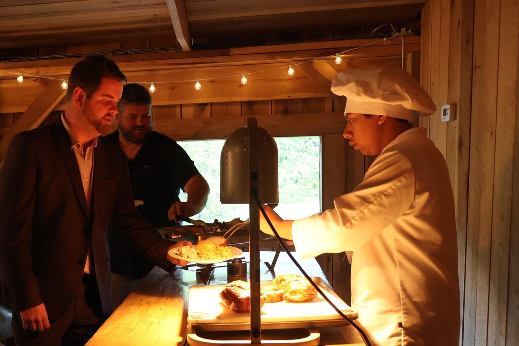 A student serves pork loin to guests.