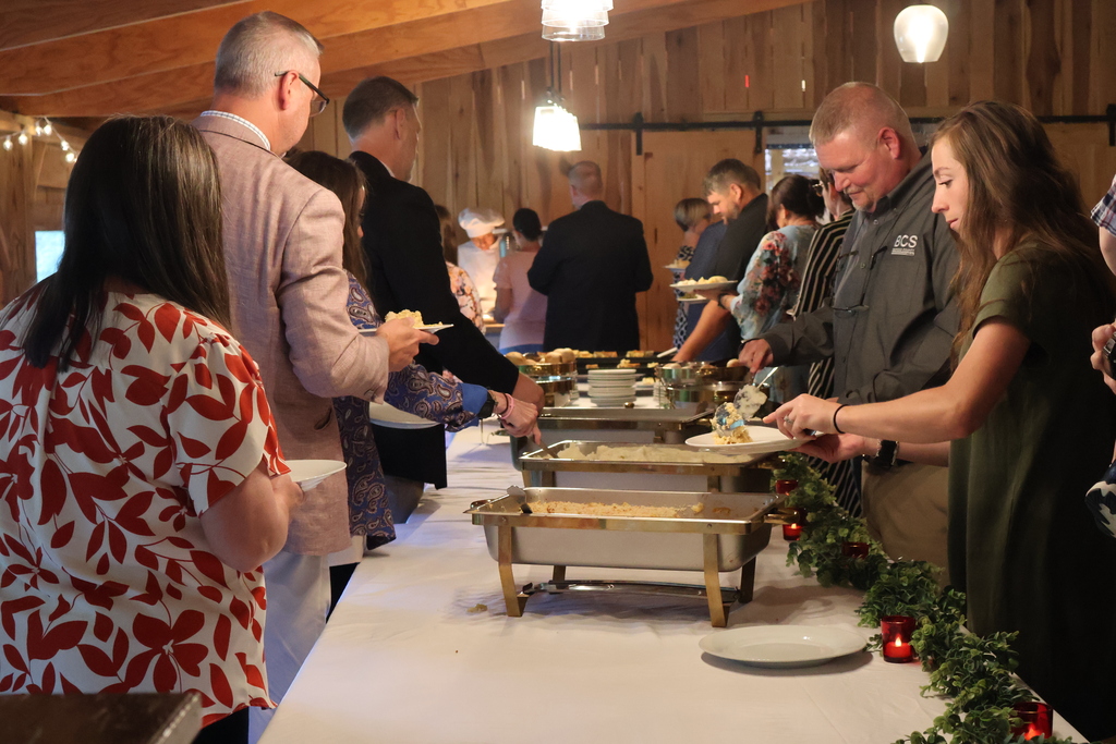 The buffet style table where people were on either side putting food on their plates.