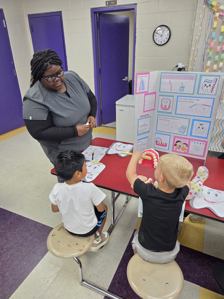 Two Pre-K students are learning about healthy mouth care from a high school student.
