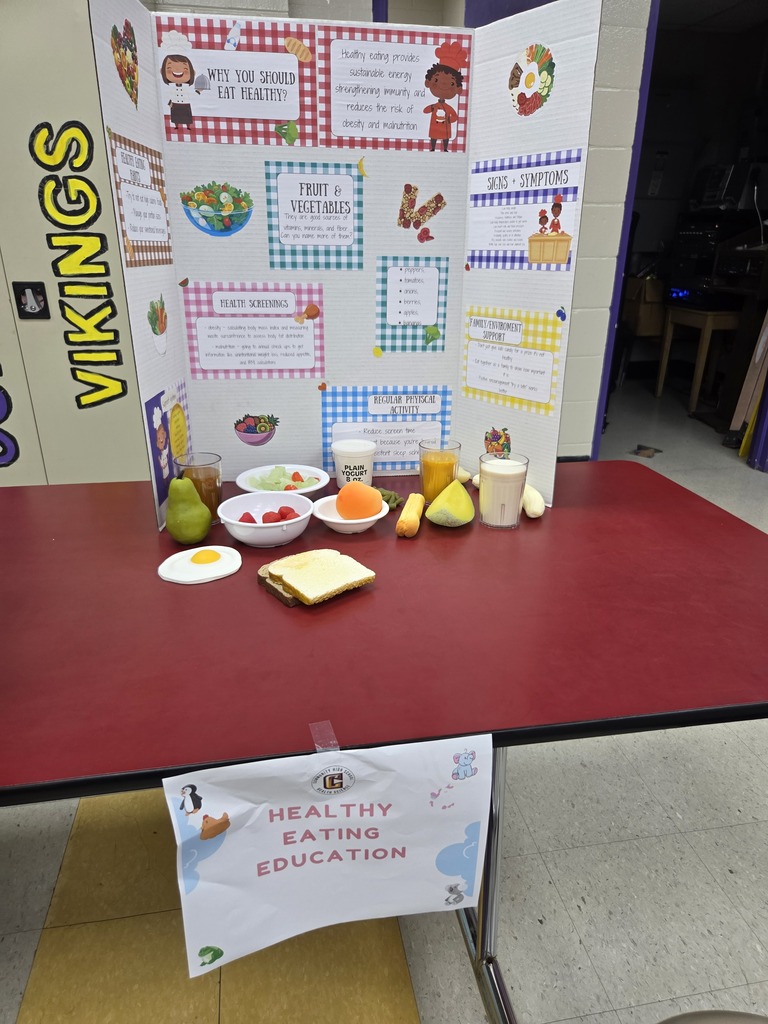 Healthy eating education set up that includes a large poster with information as well as some fake foods that are set out as an example. 
